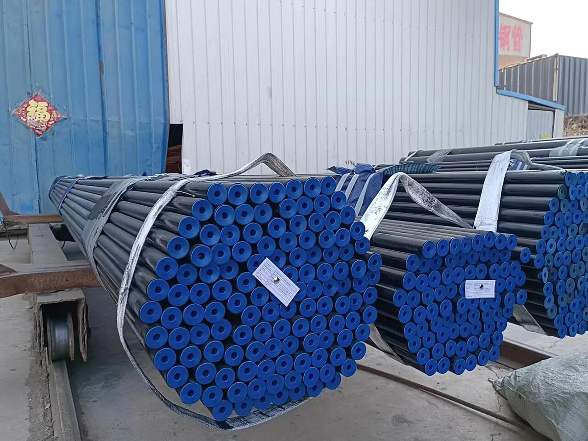 Bundles of black seamless steel pipes strapped on a truck with blue end caps